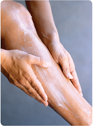 photo close up of woman spreading cream on her leg