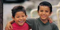 Two young boys with arms around shoulders and smiling