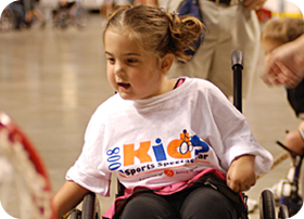 Image of a very young girl smiling while she plays wheelchair tennis. Link to full story