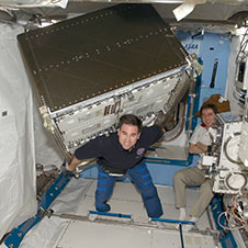 iss017e014091 -- Greg Chamitoff appears to carry a huge load though microgravity renders the experiment rack weightless