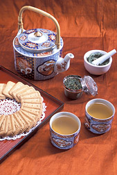 Photo: Tea kettle, tea leaves, two cups of tea, and cookies. Link to photo information