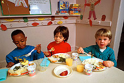Tres niños comen una comida. Enlace a la información en inglés sobre la foto