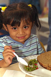 Niña preescolar comiendo. Enlace a la información en inglés sobre la foto