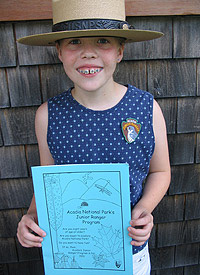 A new junior ranger proudly displays her new patch and book.