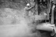 Worker in cloud of dust operating a drill