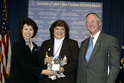Secretary of Labor Elaine L. Chao (L) and Assistant Secretary of Labor for Disability Employment Policy Roy Grizzard (R) present a 2003 Secretary of Labors New Freedom Initiative Award to Diana L. Drews, Executive Director, Sensory Access Foundation. (DOL Photo/Shawn Moore)