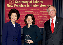 Secretary of Labor Elaine L. Chao (L) and Assistant Secretary of Labor for Disability Employment Policy Roy Grizzard (R) present a 2004 Secretary of Labor's New Freedom Initiative Award to Pamela Passman (center) Deputy General Counsel Microsoft Corporation
