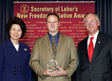 Secretary of Labor Elaine L. Chao (L) and Assistant Secretary of Labor for Disability Employment Policy Roy Grizzard (R) present a 2004 Secretary of Labor's New Freedom Initiative Award to Jason Korte (center) Co-Owner A & F Wood Products, Inc.