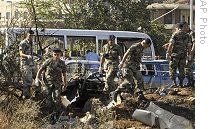 Lebanese soldiers inspect the site of explosion near a damaged bus in the northern city of Tripoli, Lebanon, Monday, Sept. 29, 2008