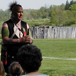 Park Ranger in historic Eastern Woodland Indian costume presenting talking with park visitors.