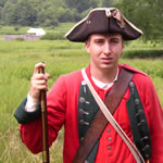 Volunteer British re-enactor in meadow with Fort Necessity in background