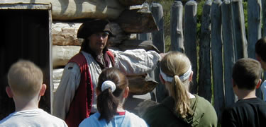 A costumed interpretor speaks with a group of children at Fort Necessity