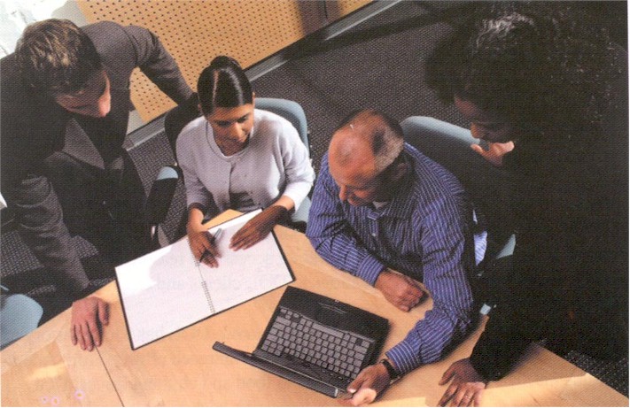 Picture of a group of people looking at information on a laptop computer