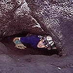 Person crawling out from a cave passage.