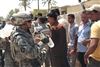 U.S. Army Staff Sgt. Fred Hampton hands out water to Iraqi men that are applying to be members of a new "Sons of Iraq" neighborhood watch program in the Sadr City district of Baghdad, Iraq, May 30, 2008. Hampton is assigned to the 1st Battalion, 6th Infantry Regiment. More than one-hundred young Iraqi men showed up at the school to apply for an opportunity to be part of the program. 