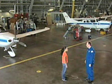 A student talks with a pilot in an airplane hangar
