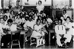 Black children sitting in desks in classroom with teacher