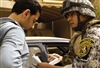 An Iraqi National Police officer questions a driver's paperwork during a cordon and search mission in Baghdad, Iraq, March 15, 2008. The search mission for illegal firearms and improvised explosive device caches is being conducted with U.S. Army soldiers assigned to the 10th Mountain Division's 5th Battalion, 25th Field Artillery Regiment.