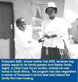 Thokozani (left), whose mother has AIDS, receives vegetable seeds for his family garden from Nestar Twala (right), a Child Care Forum worker, outside his new home in South Africa. The program has also negotiated a waiver of Thokozani’s school fees and helped the family find new housing.