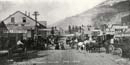 historic photo of Skagway, AK showing horses and ladies with long dresses in mud street