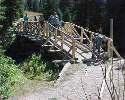visitors using a wooden bridge across a creek