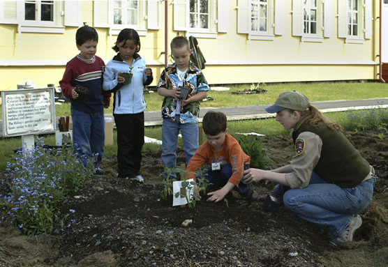 School children learn to garden with the help of a NPS volunteer.
