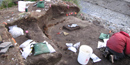 An archeologist excavates a house pit overlooking a stream.