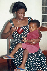 Photo of a woman in Africa feeding her infant a chlorquine tablet.