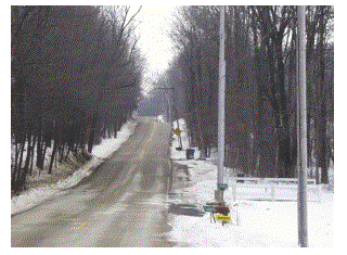 An empty two-lane road through the trees in the wintertime with mailboxes on the side