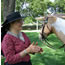 Woman in 1800s costume standing next to horse.