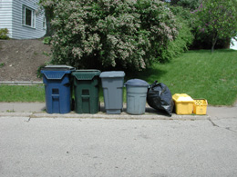 Trash cans on sidewalk next to recycling bins outside a home