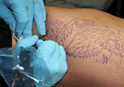 imagen de las manos de un artista del tatuaje utilizando guantes para aplicar la tinta