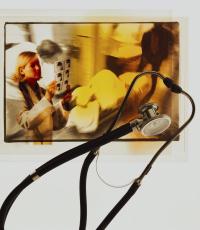 Fotografía de un estetoscopio con la imagen de un doctor y un paciente grave al fondo
