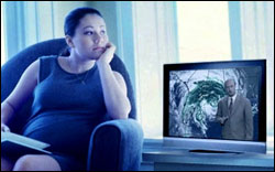 Photo: A pregnant woman listening to the news on TV.