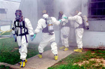 Photo of four people in HazMat suits outside a building.