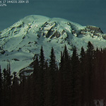 Mount Rainier on a clear day with trees in foreground. Taken from the MountainCam at Paradise.