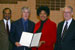 Congresswoman Watson presents a congressional resolution to USC football coach Pete Carroll in recognition of USC’s national champion football season (2004).  From left to right: Mike Garrett, USC Athletic Director; Coach Pete Carroll, USC football; Congresswoman Watson; and Dr. Steven Sample, President, USC. The resolution also acknowledges USC’s national women’s volleyball and men’s water polo national championship seasons.