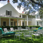 A circle of lawn chairs under the shade in front of the Texas White House