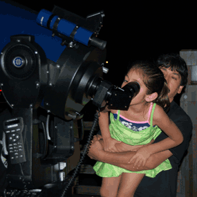 A father helps his daughter peer at the night sky through a large telescope at one of the park's star parties during the summer of 2006.