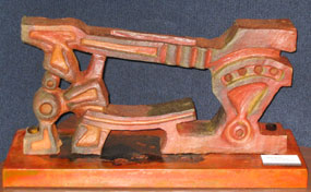 Orange ceramic sculpture of a floor-mounted iron cutting blacksmith tool.