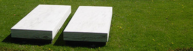 Large but simple white stone slabs mark two graves.