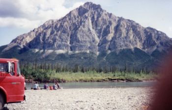 Workers eating lunch near the river. There is a mountain in the background