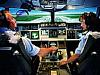Two pilots sit at the controls of an airplane simulator
