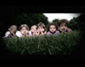 Children laying on grass with hand holding heads