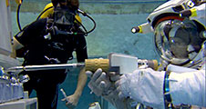 An astronaut uses a power tool during training in the Neutral Buoyancy Lab
