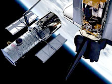 The shuttle's robotic arm grapples Hubble