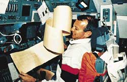 An apparently weightless floating makes some tasks challenging inside an orbiting spacecraft. In this photograph, a shuttle astronaut struggles with a floating computer printout.