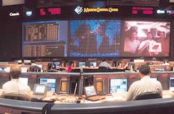 A mission control facility on the earth supervises the activities of astronauts in space.
