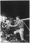 [Charles Lindbergh, 1902-1974, three-quarter length portrait, standing, left profile, working on engine of "The Spirit of St. Louis"]