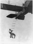 ["Fearless Freddie," a Hollywood stunt man, clinging to a rope ladder slung from a plane flown by A.M. Maltrup, about to drop into automobile below: automobile not shown]
